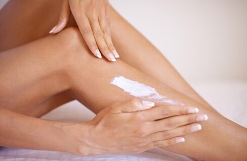 Mujer aplicando crema hidratante corporal en su pierna