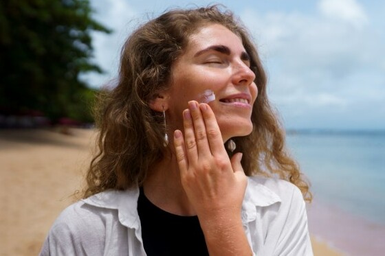 Mujer aplicando protector solar facial con color en su rostro