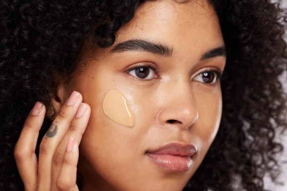 Mujer aplicando protector solar facial con color en su rostro