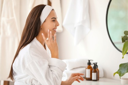 Mujer joven aplicándose productos de dermocosmética facial